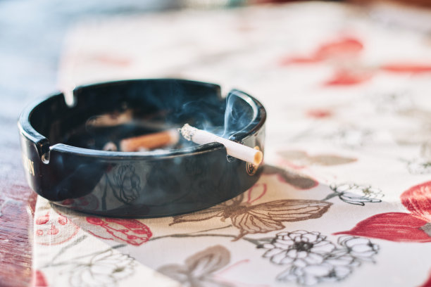 烟灰缸里燃烧着的香烟和日落时的烟雾图片下载