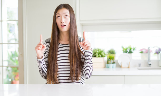 美丽的亚洲女人穿着条纹毛衣惊讶和惊讶的看着和指着手指和举起的手臂。图片下载