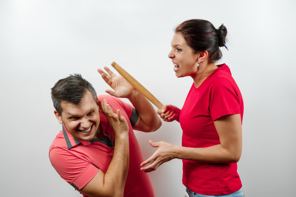 家庭吵架，妻子骂丈夫，年轻漂亮的妻子用棍子打丈夫。家庭关系、婚姻、家庭冲突、图片下载