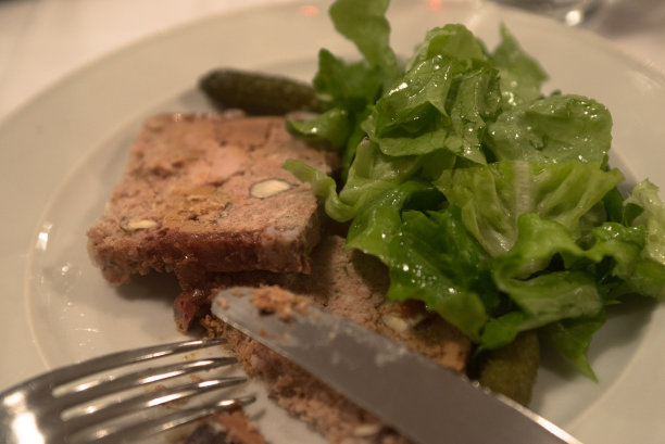 在巴黎餐厅里，把Paté切片放在配有绿色蔬菜的盘子里图片下载