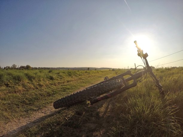 骑山地车在乡间小路上，身后是太阳图片下载