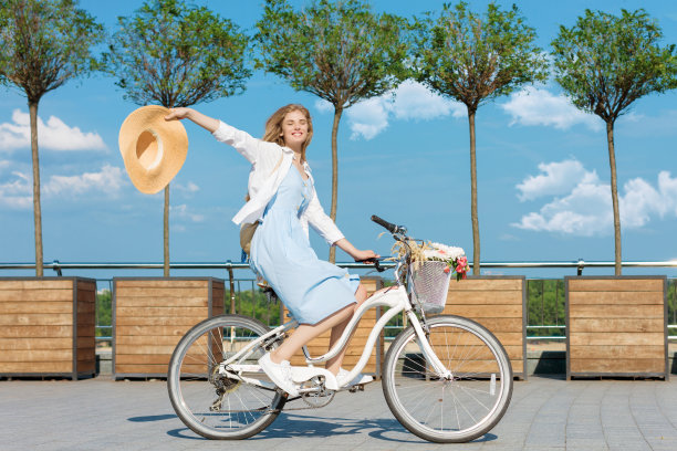 一个女人穿着蓝色的衣服骑着白色的花篮骑车图片下载