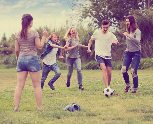 青少年在公园里踢足球图片下载