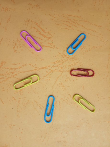 照片平铺橙色纸与红蓝黄回形针，为您的背景，背景，信息，引用等图片下载