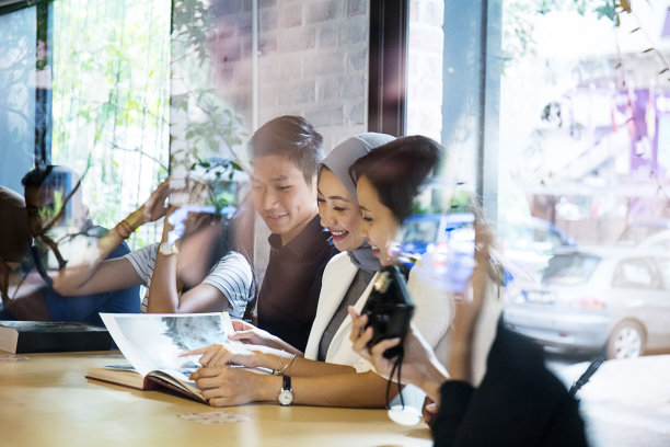 年轻人朋友聚会，穆斯林妇女在自助餐厅看杂志图片下载