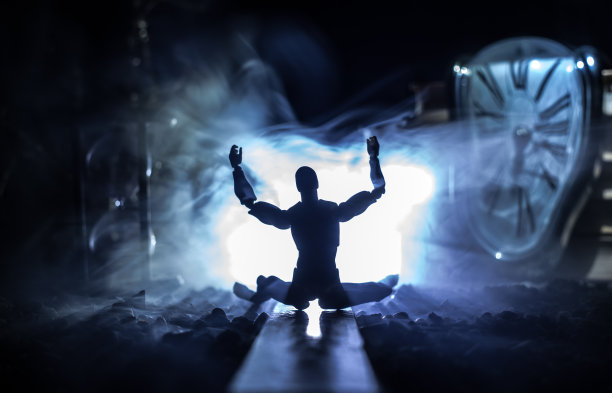 时间的概念。一个男人的剪影站在沙漏中间，在黑暗的背景上有烟雾和灯光。超现实主义的装修图片图片下载