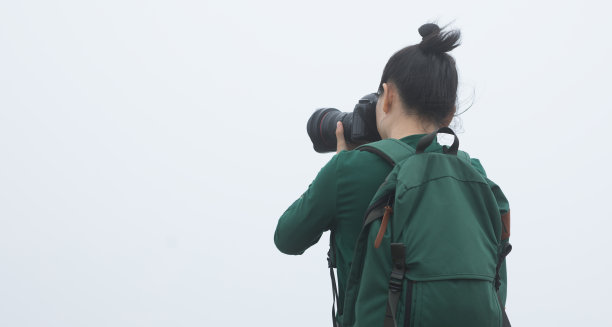 女摄影师在春天雾蒙蒙的森林山拍照图片下载