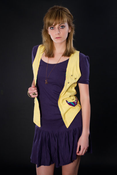 华丽的年轻女子工作室时尚图像在黑暗的背景下摆姿势，而穿着休闲服装看着相机，眼睛睁得大大的。图片下载