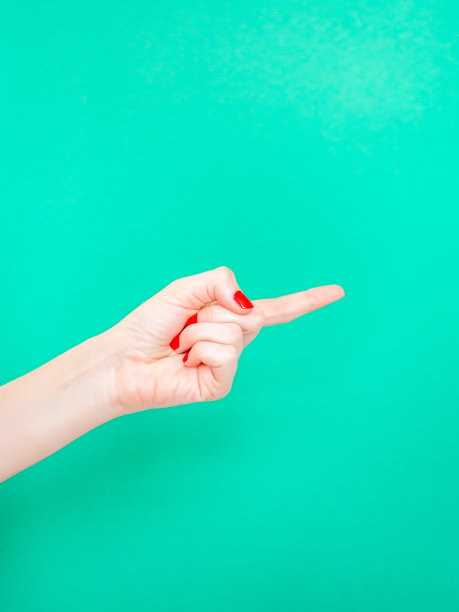 看这个手势。女性手指指孤立在明亮的绿松石背景。图片下载