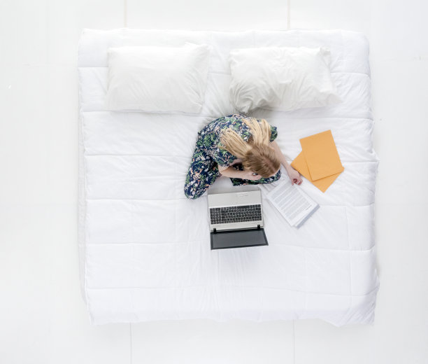 可爱的女性在床上做工作/作业图片下载