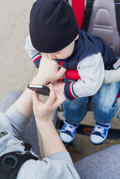 小男孩坐在婴儿车里看手机图片下载