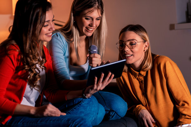 三个女性朋友正在玩卡拉ok。素材图片