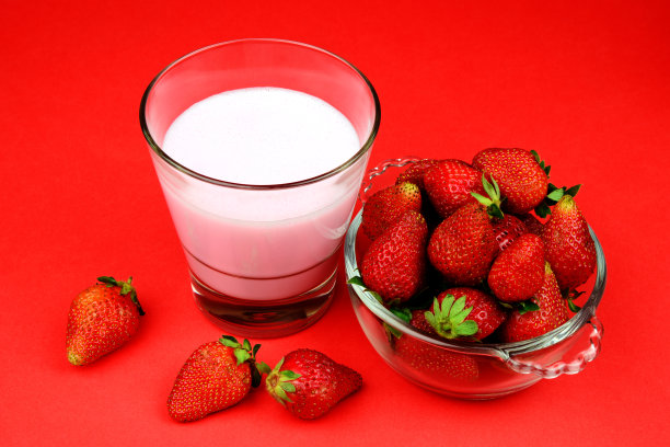 鲜嫩多汁的熟透草莓放在玻璃杯里，配上一杯奶昔图片下载