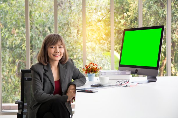 女商人在电脑前工作，思考项目，看手机上的信息，桌子上装饰着鲜花和办公设备图片下载