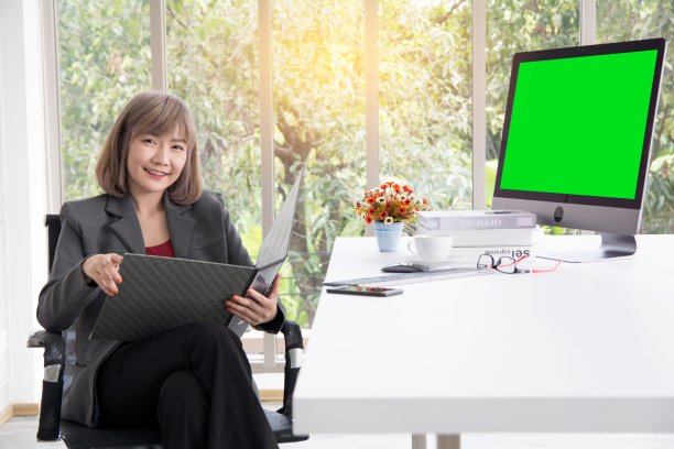 女商人在电脑前工作，在用鲜花和办公设备装饰的桌子上阅读和思考项目图片下载