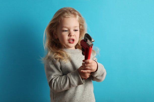可爱的小女孩拿着扳手工具。小助手和乐趣图片下载