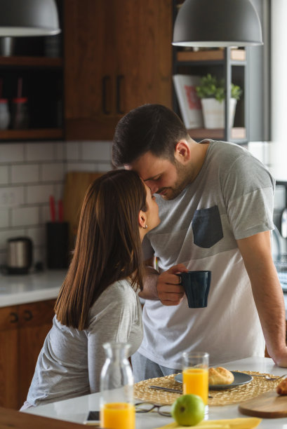 年轻英俊的夫妇早上穿着睡衣在家吃早餐。向对方表达爱意。图片下载