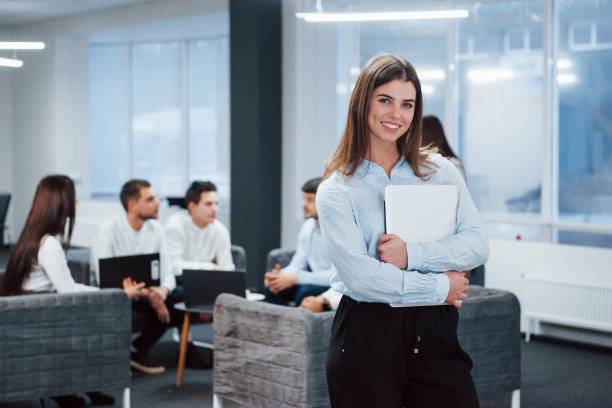 经典的穿。一幅年轻女孩的画像站在办公室里，背景是员工图片下载