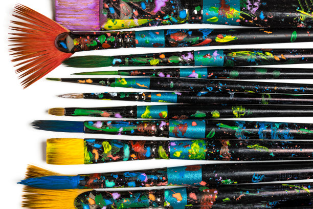 在白色背景上隔离的一排染色画笔。艺术背景图片下载