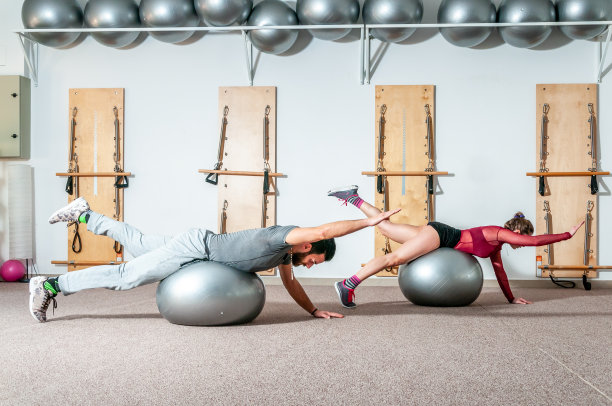 积极和活跃的年轻美丽瑜伽健身夫妇锻炼极限杂技运动，对普拉提球作为准备比赛，选择性的重点图片下载