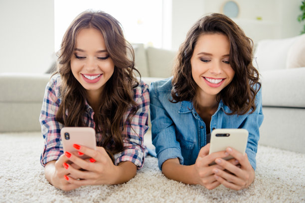 近距离的照片美丽的她，她的女士们的朋友，伙伴，聚会，收集电话，手，手臂，读者，电子邮件，穿着休闲的牛仔裤，粗斜纹棉布格子衬衫，公寓，躺在地板上，沙发房间，室内图片下载