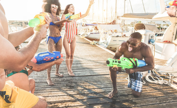 快乐的朋友们做战斗派对与水枪-年轻的千禧一代在暑假里大笑和有乐趣-青春，生活方式和假日概念-专注于左手图片下载