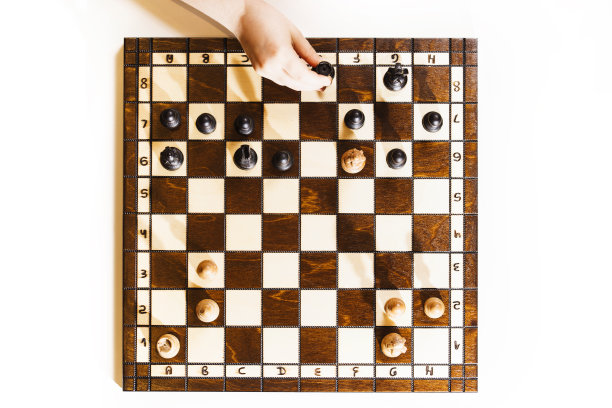 白色背景的棋盘。一个白人小女孩手里拿着一座黑色城堡。前视图。图片下载