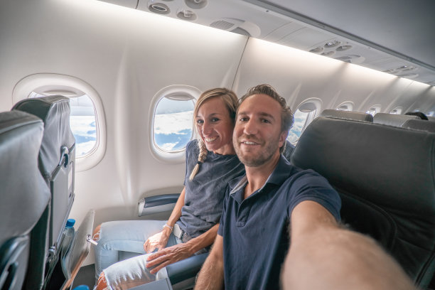 年轻夫妇在飞机上自拍，准备度假图片下载