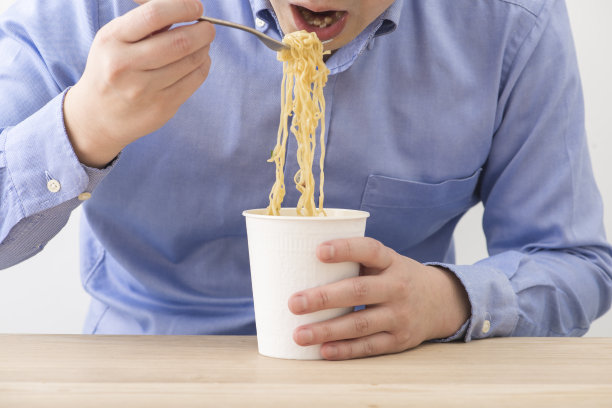 一个人在吃一杯方便面。素材图片