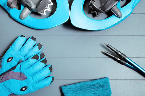 平顶视图冬季登山设备和装备，如雪鞋，登山杆和蓝色手套。雪上运动和娱乐的概念图片下载