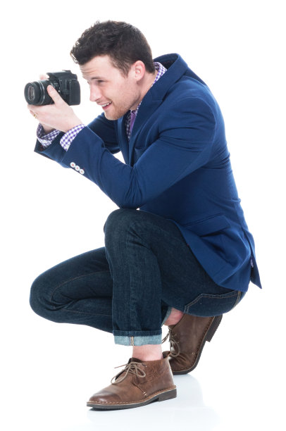 侧视图的英俊男子蹲着，同时拿着单反相机图片下载