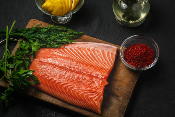 一片三文鱼片在一个木制砧板上与原料进一步准备，俯视图-照片，图像图片下载