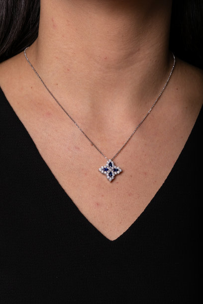 银色的母链和一个花朵形状的垂饰，脖子上挂着蓝色的宝石。图片下载