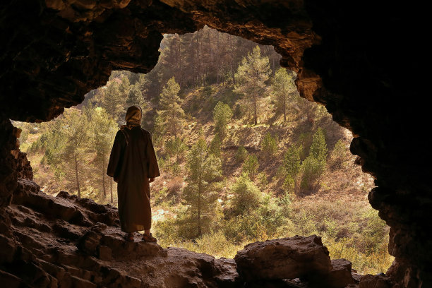 一名男子戴着头巾，从一个有树的山洞里往外看图片下载
