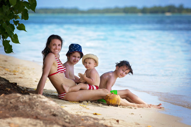 幸福的一家人，怀孕的母亲和三个孩子（男孩）在毛里求斯的海滩上玩耍图片下载