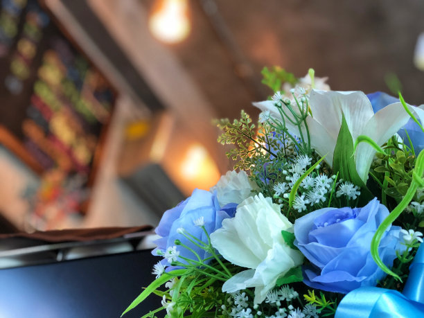 花，白色和蓝色调，人造花。蓝色的玫瑰，白色的百合花和咖啡灯图片下载