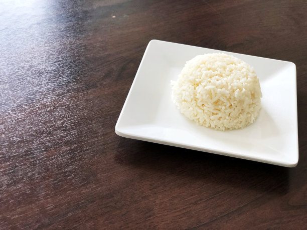 米在白方盘上，深色木桌上透出自然光。即食，拷贝空间，亚洲主要食品图片下载