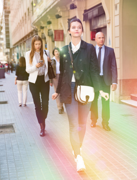 时尚的年轻商务女性穿着休闲服装走过城市街道在人群中图片下载