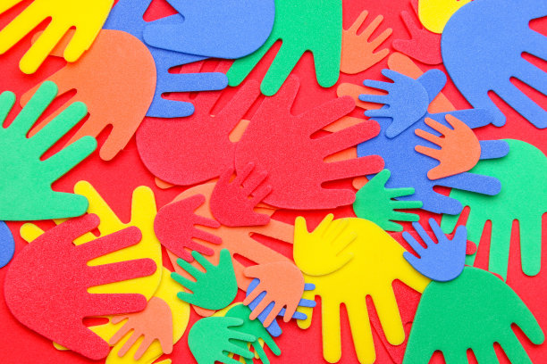 泡沫剪出红色、橙色、黄色和绿色的奇特手形，在朴素的背景上图片下载