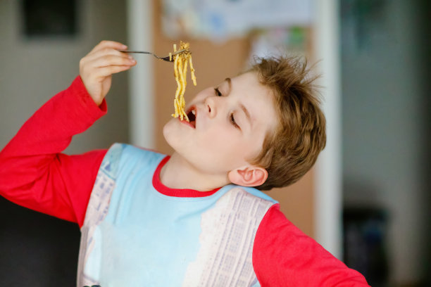 可爱健康的学前班小男孩坐在学校或托儿所的咖啡馆里吃面条。快乐的孩子在餐厅或家里吃健康的有机和素食食品。童年,健康概念图片下载