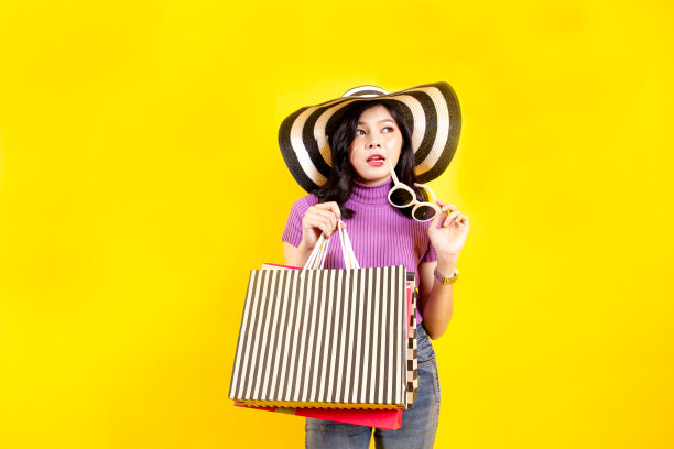 亚洲女孩的肖像与购物袋近距离彩色的背景。图片下载