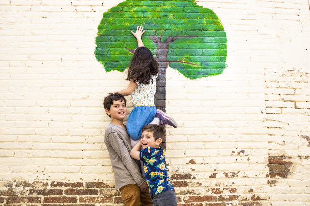 三个孩子在玩画在墙上的树图片下载