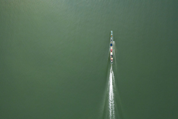 (俯瞰)一艘传统的长尾船与一名当地人在老挝北部塔拉特南郁水库水域捕鱼的令人惊叹的鸟瞰图。图片下载