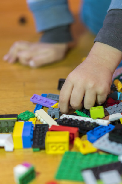 地板上五颜六色的塑料砖的特写。早期的学习。地板上的儿童塑料构造器。孩子们的手是一个小小的构造器。垂直的照片。图片下载