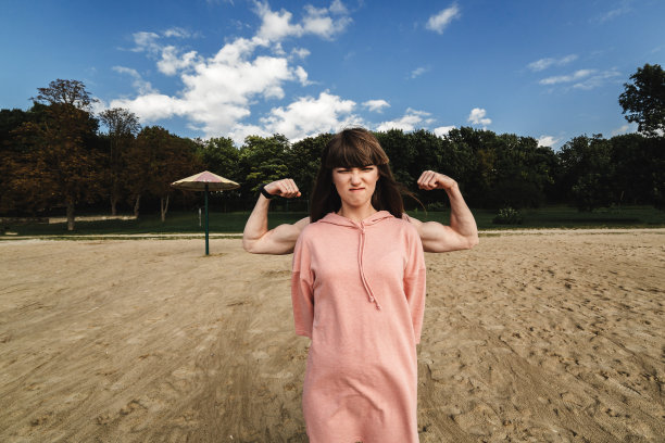 那个女孩露出了她的肌肉。精力充沛的年轻夫妇。一个穿着夏装的女人露出了肱二头肌。强壮的黑发。身材苗条，双手强壮的女孩。女孩后面的那个人露出了二头肌图片下载