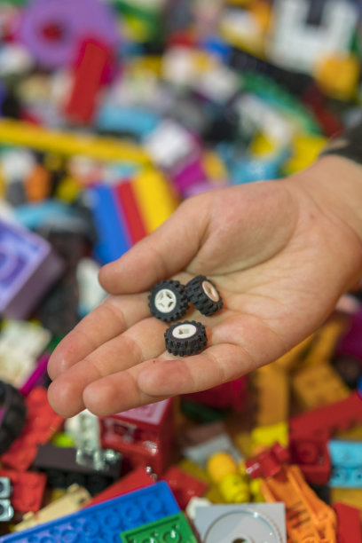 地板上五颜六色的塑料砖的特写。早期的学习。地板上的儿童塑料构造器。孩子们的手是一个小小的构造器。垂直的照片。图片下载