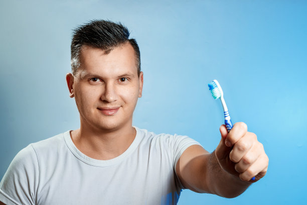 一个男人拿着牙刷在刷牙。口腔卫生的概念。图片下载