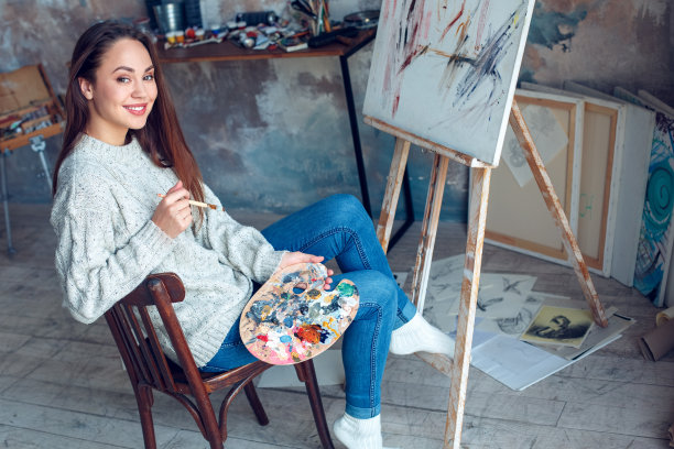 年轻女子画家在家里作画，富有创意，笑容开朗图片下载