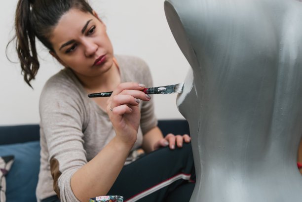 年轻的成年女性设计师用丙烯颜料画人体模型图片下载