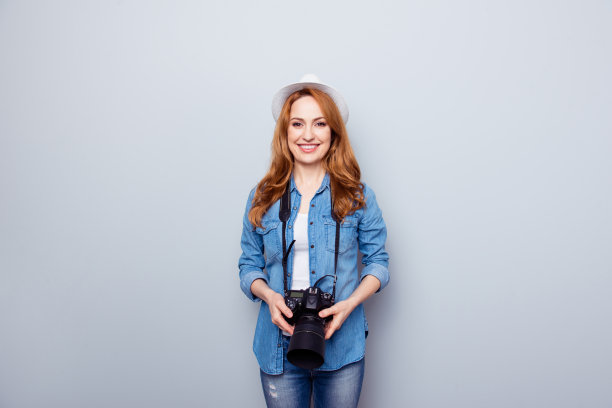 近距离的照片美丽有趣，时髦的她她的夫人牙齿旅行者照片手手臂相机使采取创造性的图像现代科技穿眼镜休闲牛仔裤牛仔衬衫孤立的灰色背景图片下载
